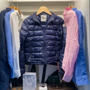 Moncler pufferjacka  - Säljer en blå pufferjacka från Moncler med klassisk quiltad design och dragkedja framtill. Jackan har Moncler-logga på ärmen. Perfekt för höst, vår och tidig vinter. Jackan är såklart äkta (se på bild 3) jackan är L-XL i barn Och XXS-XS i män. Jackan passar alla mellan 155-170. Jackan är använd ett fåtal gånger och är nästan helt nytt skick. Jackan kostar runt 5500 nypris. Pris kan diskuteras kom vid minsta fråga🤝☺️
