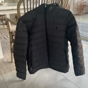 Grå dunjacka från Polo Ralph Lauren - Tjena! Säljer nu min Ralph lauren jacka. Den är använd sparsamt och är i gott skick.  Storlek: M  NYPRIS: 2800kr Finns en liten slitning (sista bilden) vid början av dragkedjan men den har ingen påverkan på jackans funktion och syns inte på utsidan. Jackan går att göra till en liten väska med hjälp utav ett snöre i höger ficka. Hör av er vid funderingar!
