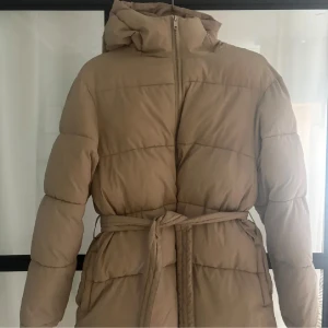 Vinterjacka med knytning från Nelly - Säljer en exakt likadan jacka fast i svart/mörkgrön. Storlek: S Har en sminkfläck i kragen, har inte försökt tvätta men går nog att få bort. Lånade bilder‼️