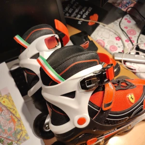 FERRARI Inline Rullskridskor justerbar storlek 38-41 - Äkta Ferrari Scuderia rullskridskor i rött, svart och vitt med italienska flaggan. Skorna har mesh- och syntetmaterial, robusta spännen och snörning för extra stöd. Dekorerade med Ferrari-logga och italienska flaggan på hälen. Perfekt för dig som gillar fart och cool stil. Just ar storlek mellan 38 till 41. Kanonskick. 