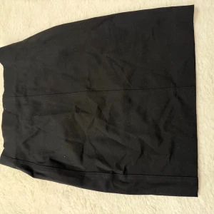 Svart kortkjol från H&M XS - En stilren svart kortkjol från H&M i storlek XS. Kjolen har en rak och enkel form, tillverkad i mjuk bomull med lite stretch för skön passform. Perfekt att matcha med sneakers eller boots för en clean look.