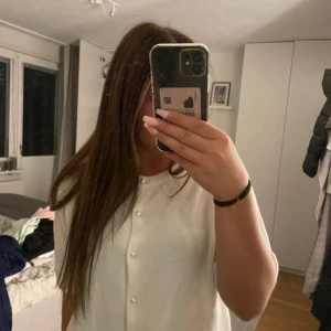 Vit kofta med pärlknappar - Superfin vit kofta med kort ärm och rund halsringning. Koftan har snygga pärlknappar framtill och är stickad i ett mjukt material som känns lyxigt. Perfekt att slänga över en topp för en söt och stilren look. Stickad t-shirt m.pärlor från lager 157 st M Endast testad