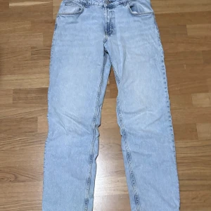 Ljusblå tapered jeans från H&M - Säljer ett par ljusblå jeans från H&M med relaxed fit och justerbar midja. Modellen har tapered ben och klassisk femficksdesign. Perfekta för dig som gillar en avslappnad stil med lite smalare ben. Materialet är klassisk denim. Bra skick 