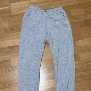Grå mjukisbyxor från Kappahl, stl 164 - Grå mjukisbyxor från Kappahl i storlek 164. Byxorna har resår och snörning i midjan samt fickor på sidorna. Perfekta för chill dagar eller när du vill vara extra bekväm. Tillverkade i mjukt bomullsmaterial.