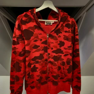 Bape hoodie  - Säljer en ikonisk röd camo hoodie från Bape med dragkedja och huva 