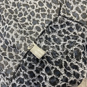 Leopardmönstrad halsduk från Infiniti - Stilren fyrkantig halsduk från Infiniti i svart, grått och vitt leopardmönster. Halsduken är ca 50x50 cm och tillverkad i tunn, lätt polyester som ger en luftig känsla. Perfekt accessoar för att lyfta din outfit med lite edge.