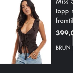 Brun omlottopp med volang från Miss Selfridge - Supersnygg brun omlottopp från Miss Selfridge med volangdetaljer och snörning framtill. Toppen har djup v-ringning och är ärmlös, perfekt att styla med jeans eller kjol. Materialet känns lätt och skönt mot huden. EY ANVÄND!