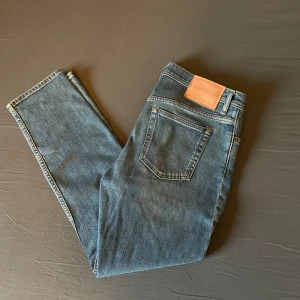 Acne Studios jeans - Säljer ett par klassiska blå jeans från Acne Studios i modellen River Mid Blue. Jeansen har en rak/slim, normal midja och är tillverkade i bomull med stretch. Snyggt läderpatch bak och diskret tvättad look. Perfekta för dig som gillar stilrena och tidlösa jeans. Ny pris 3600:-, mitt pris 899:-. Hör av dig vid minsta lilla fråga😊 4 nya plagg ligger ute!