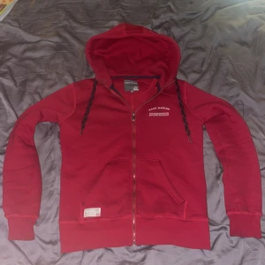 Röd hoodie från Race Marine - Röd hoodie från Race Marine med dragkedja, huva med svarta snören och broderad logga på bröstet. Mjuk insida och två fickor framtill. Perfekt för chill dagar. SKRIV VID MINSTA FRÅGA, PRIS KAN DISKUTERAS. 