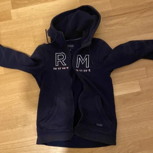 Race Marine hoodie - Mörkblå hoodie från Race Marine i storlek XS. Tröjan har dragkedja, huva med snörning och två fickor framtill. Snyggt broderade bokstäver och koordinater på bröstet ger en sportig vibe. Perfekt för kyliga dagar.