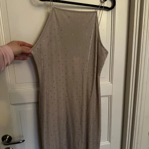 Beige glittrig klänning med smala band - Säljer en beige klänning med smala axelband och glittriga detaljer över hela tyget. Samet