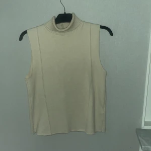 Beige polotopp från Zara - Säljer en beige polotopp från Zara i storlek S. Toppen är ärmlös med hög polokrage och har en mjuk, stickad känsla. Är i super bra skick knappt några tecken på användning, så den är inte alls ofta använd.❣️