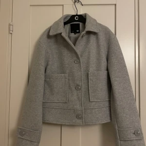 Ljusgrå kappa - En superfin ljusgrå, kort kappa som passar perfekt till hösten!🍁🍂 Kappan har aldrig använts innan och är i helt nytt skick, dock saknas prislappen. Storlek XS