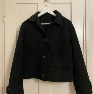 Svart kappa - En superfin svart, kort kappa som passar perfekt till hösten!🍁🍂 Den saknar en knappdetalj på vänstra armen, annat än det så är kappan i bra skick :) Storlek S