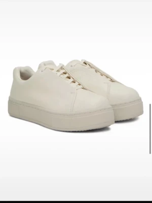 Skor eytys  - Säljer ett par sneakers från Eytys med platt sula och snörning. Skorna är tillverkade i skinn och har en mörklila detalj på hälen samt Eytys-logga på baksidan och undersidan. Insidan har korkinlägg och klassisk rund tå. Tecken på användning finns men är fortfarande i fint skick!