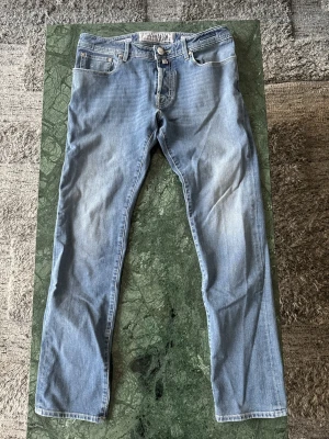 Jacob Cohen jeans - Säljer ett par ljusblå jeans från Jacob Cohen med klassisk femficksdesign och diskret broderad logga på myntfickan. Jeansen har normal passform, raka ben och är tillverkade i mjukt bomullsmaterial med stretch. Perfekta för en avslappnad och stilren look. Hör av dig vid funderingar!🤩