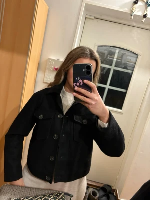 Svart summerjacket - Säljer en svart kort jacka från vero mods med klassisk krage och stora bröstfickor med lock. Jackan har knäppning framtill med stora knappar och är i en lite boxig, croppad modell. Perfekt att slänga över en hoodie eller t-shirt för en chill look. Lite nopprig här och där kan säkert rakas bort annsrs fin! (Har en liknande i flödet som är i topp skick! i mocka imitation vid intresse) nypris 500kr
