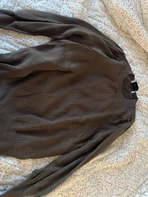 Brun ribbad tröja från Neo Noir - Säljer en brun ribbad tröja från Neo Noir i storlek XS. Tröjan har långärmad design, rund halsringning och är gjord i ett mjukt stickat material. 