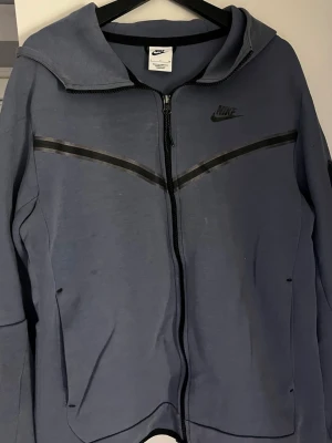 Nike tech hoodie S  - Säljer en ljusblå Nike tech hoodie. Den är stor i storleken. Hoodien är använd ett tag och är nopprig längst ner på ärmarna , färgen är lite uttvättad. Därför säljs den billigt. 