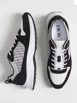 Svarta och vita sneakers från Dior - Snygga sneakers från Dior i svart och vitt med klassisk logotyp på sidan. Skorna har snörning, rund tå och en tjock vit sula. Materialmix av skinn och textil med detaljer i mocka. Perfekta för dig som vill ha en stilren och lyxig look.