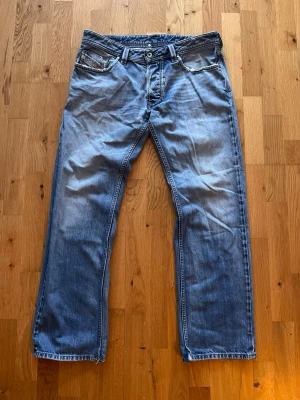 Blå Diesel jeans straight fit - Säljer ett par klassiska blå jeans från Diesel med straight fit, nästan lite flare. Jeansen har slitna detaljer vid fickorna och tydliga sömmar på bakfickorna. Pris kan såklart diskuteras vid snabb affär och det är bara att skriva vid frågor.
