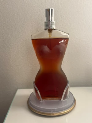 Jean Paul Gaultier Eau de Toilette - 100 ml Eau de Toilette från Jean Paul Gaultier, tillverkad i Frankrike. Flaskan har en unik design och är perfekt för dig som vill sticka ut med din stil. Stått i ett skåp i badrummet. Vet inte hur gammal den är då jag fått den av min mormor. Den har mörknat i färgen därav priset. Förpackningen medföljer. Lukten kan ha ändrats något då den stått i några år orörd. Också därav priset 