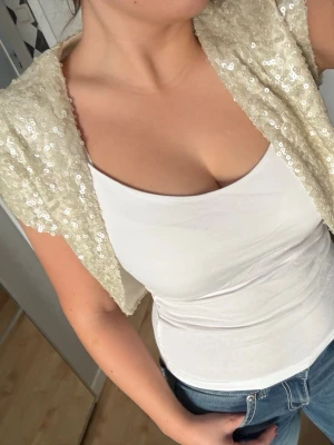 Paljettbolero  - Säljer en kort, glittrig bolero med paljetter. Koftan har korta ärmar och öppen front, perfekt för att lyfta en enkel outfit. Perfekt att styla med en basic topp för att lyfta en festoutfit💕🫶🏻