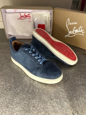 Blå sneakers från Christian Louboutin - Snygga blå sneakers från Christian Kan även ta emot byten Louboutin med klassisk röd sula och ljusblå snörning. Skorna är tillverkade i mocka med en vit platt sula och har rund tå. Insidan är beige och de levereras med originalkartong och dustbag. Kvitto och allt kommer med !👌Bara fråga om ni har någon fråga ?