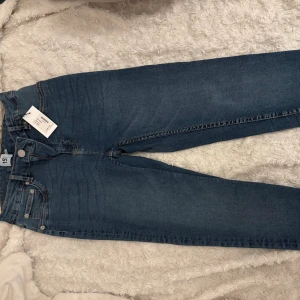 Blå jeans från 157, storlek L - Snygga blå jeans från 157 med klassisk femficksdesign och raka ben. Jeansen har en mörkblå tvätt och tydliga kontrastsömmar. Tillverkade i slitstarkt denim-material och stängs med knapp och dragkedja. Perfekta för en avslappnad och trendig look.