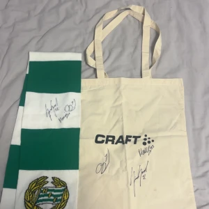 Grönvit randig halsduk Hammarby - Säljer en grön och vit randig halsduk från Hammarby IF med klubbens broderade emblem och autografer. Perfekt accessoar för att visa ditt stöd på matchen eller i vardagen. Klassisk design med breda ränder och mjukt material.
