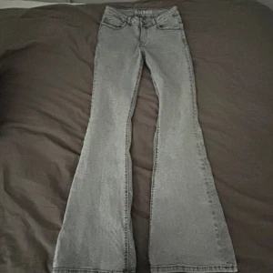 Gråa flare jeans från Blue Ridge - Snygga gråa flare jeans från Blue Ridge i storlek 164. Jeansen har klassisk femficksdesign, utsvängda ben och en cool tvättad look. Perfekta för dig som gillar retrovibbar och vill sticka ut lite extra. Materialet är mjukt och stretchigt jeans.