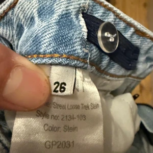 Ljusblå loose fit jeans strl 26 - Säljer ett par ljusblå jeans med loose fit och raka ben. Klassisk femficksmodell med bälteshällor och knappstängning. Jeansen har en avslappnad streetstil och är tillverkade i denim för en tidlös look.