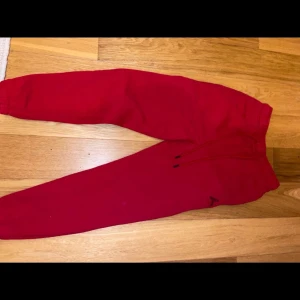 Röd hoodie och byxor från Jordan - Röd hoodie och byxor från Jordan. Klassisk logga på bröstet och stora fickor framtill. Tillverkad i mjuk bomullsblandning, perfekt för chill eller streetwear. Snygg och sportig look.