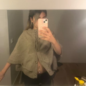 Beige stickad kofta med knappar - Säljer en beige stickad kofta med korta ärmar och knappar framtill. Koftan har en loose passform och ribbade kanter vid ärmslut och nederkant. Perfekt för hösten!!!🍂🍁