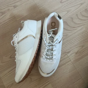 Vita sneakers från ONLY med gulddetaljer - Snygga vita sneakers från ONLY med meshpaneler och guldfärgade detaljer på häl och sidor. ALDRIG ANVÄNDA!