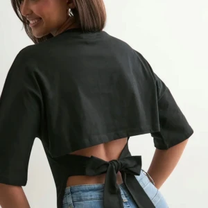 Svart croppad topp med knyt i ryggen - Säljer denna fina tröja, den kommer tyvärr ej till användning längre! Priset går att diskuteras.