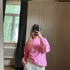 Rosa långärmad tröja med tryck - Säljer en rosa långärmad tröja med en söt liten pappersflygplans- och hjärttryck på ryggen. Tröjan har rund halsringning och avslappnad passform.