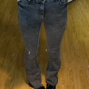 Grå bootcut jeans med råa kanter - Säljer ett par grå jeans med bootcut-modell från Berhska köpta i Tyskland. Jeansen har fickor och är mid waist. Materialet är denim i bomull och de har en snygg tvättad look som ger en cool vibe. Klippta nertill men syns inte då det ser ut som en design. 