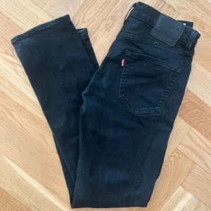 Svarta Levi's 511 jeans skinny fit - Svarta Levi's 511 jeans med skinny fit och klassisk femficksdesign. Storlek. W32, L34 Jeansen har normal midja, smala ben och är tillverkade i stretchig bomullsdenim för en bekväm passform. Perfekta svarta jeans med diskret Levi's-lapp och röd etikett på bakfickan.