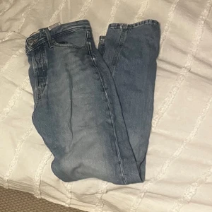 Blå jack&jones jeans W28 L32 - Klassiska blå jack&jones jeans i rak modell. Jeansen har fem fickor, knappgylf och är tillverkade i slitstarkt denim. Perfekt passform med normal midja och raka ben. Snygg tvättad blå färg som passar till allt.