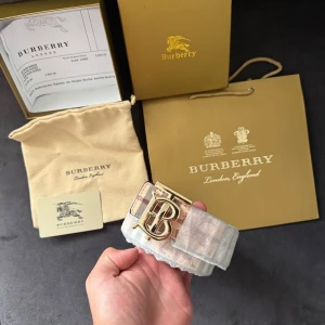 Burberry bälte - ✨ Tvåsidigt Burberry-bälte i klassiska rutiga Nova Check-mönstret. ✨ Elegant guldfärgat TB-spänne. ✨ Kommer med originalförpackning, dustbag och påse  📏 Storlek: 110cm 🛍 Skick: helt ny