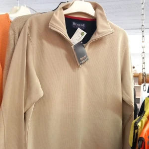 Beige half zip tröja Headline Classics - Beige långärmad tröja från Headline Classics med stilren half zip-dragkedja och hög krage. Tröjan är i ett mjukt bomullsmaterial och har en enkel, clean look som passar perfekt till jeans eller chinos.