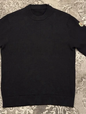 Moncler tröja - Svart fin stilren stickad tröja med rund halsringning och ribbade muddar. Klassisk design med Moncler-logga på ena ärmen. Perfekt för dig som gillar stilrena och exklusiva plagg, pris kan diskuteras vid snabb affär.