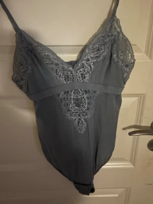 intimissimi spetsbody - Supersnygg blå body från Intimissimi med tunna axelband och vackra spetsdetaljer framtill. Tillverkad i mjuk bomull som känns skön mot huden. Perfekt att styla lager på lager eller bära som den är. Stretchig.
