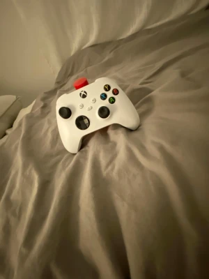 Vit Xbox Series-handkontroll - Snygg vit Xbox Series-handkontroll med klassisk layout och svarta detaljer på styrspakar och styrkors. Knapparna har färgglada symboler och kontrollen har en modern, ergonomisk form i plast. Perfekt för gaming på Xbox eller PC. Den har lite stick drift men annars funkar den perfekta 