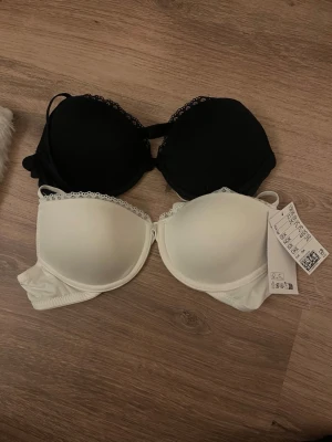 2-pack bh svart och vit med spetskant - Två bh:ar i svart och vitt med mönster upp till. Lappen är kvar.