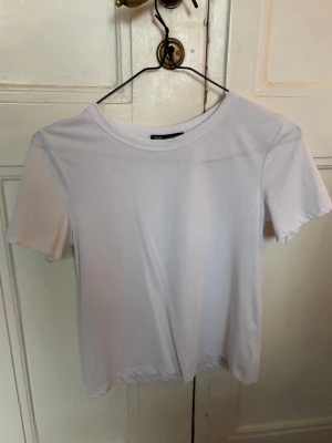 Vit croppad t-shirt från Zara - Säljer exakt likadan tröja fast i svart!! Sitter som XS/S, extremt skönt material 💞 Säljer pga för många liknande tröjor 🤗