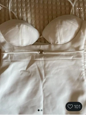 Vit topp från Zara - Säljer en vit topp från Zara med smala axelband och bygelkupor. Toppen har en snygg detalj med dragkedja framtill och figurnära passform. Perfekt för sommarens alla tillfällen!
