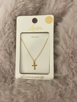 Guldpläterat halsband med kors Lovisa - Aldrig använt, köpt i Australien. Snyggt halsband från Lovisa i guldpläterat sterlingsilver med ett litet kors som hänge. Kedjan är tunn och elegant, perfekt för att ge en stilren touch till din outfit. Längd 45 cm. Enkel och modern design. 