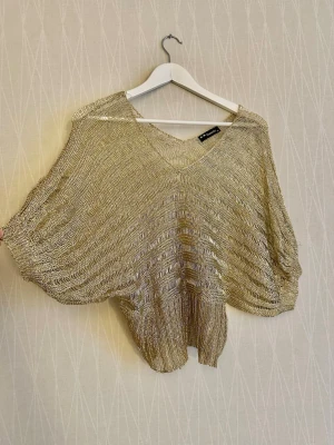 Gold-colored, open-knit metallic sweater with a fitted waist. - Gold-colored, open-knit metallic sweater with a fitted waist. It has many loose threads, which I tried to show in the pictures. Tag says L but it fits more like M